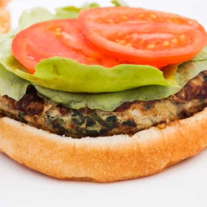 Open faced turkey burger on a bun and topped with lettuce and tomato.