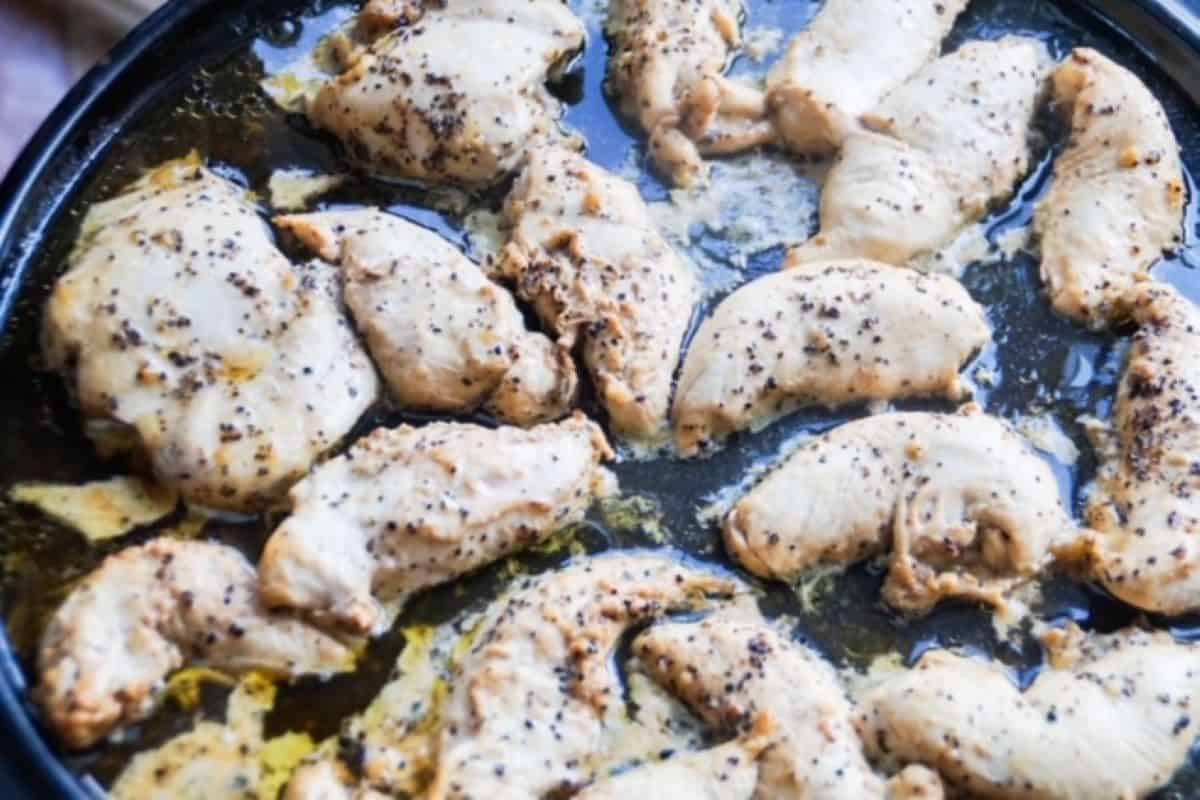 Lemon pepper chicken pieces on a black grill stone.