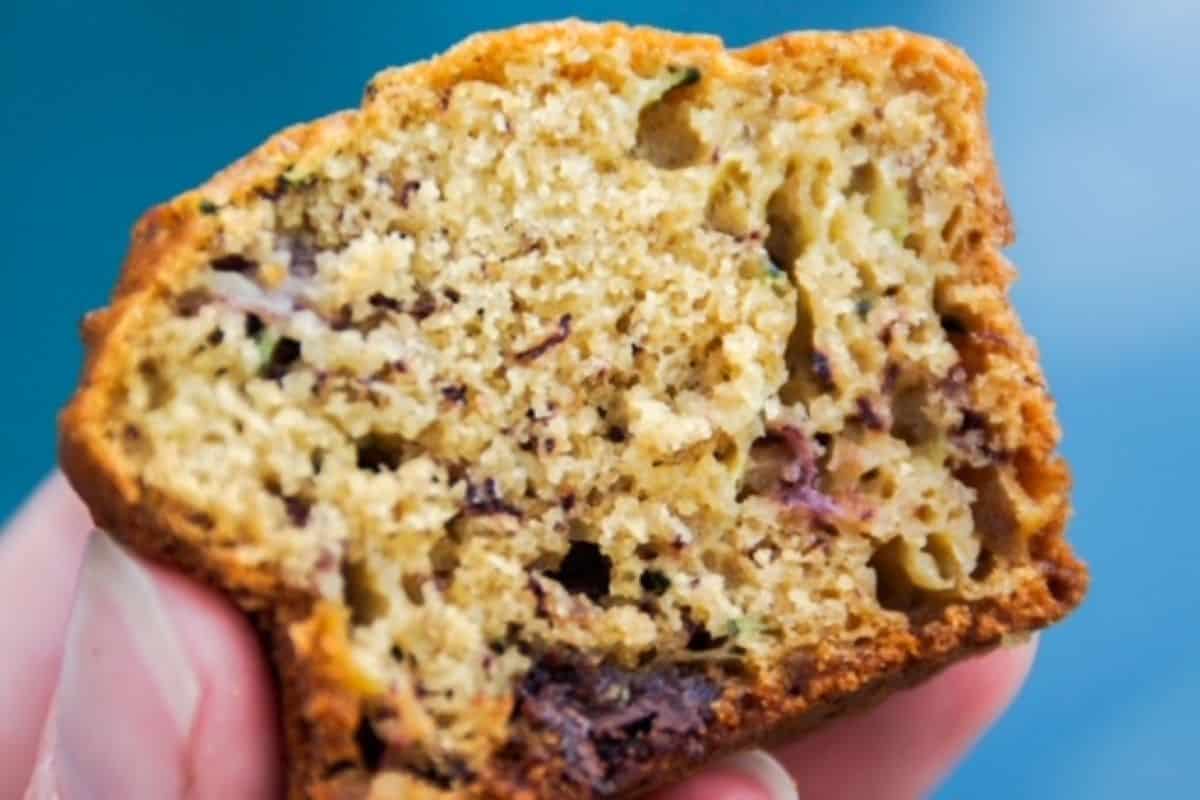 Half of a muffin being held up with blue background.