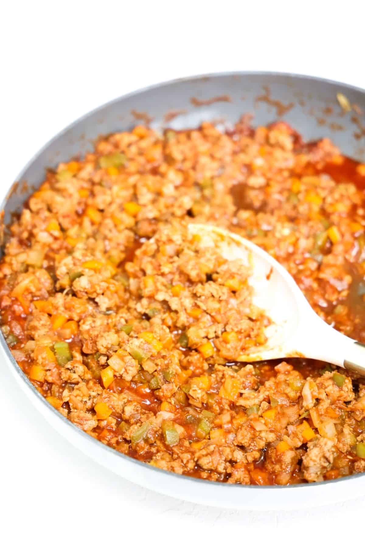 Ground turkey sloppy joe mixture in a skillet with a white serving spoon.