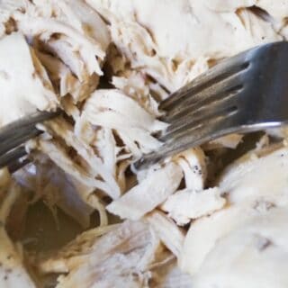 Two forks shredding chicken