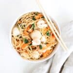 One Asian-inspired noodle bowl with a linen napkin to on the side and chopsticks on the top of the bowl.