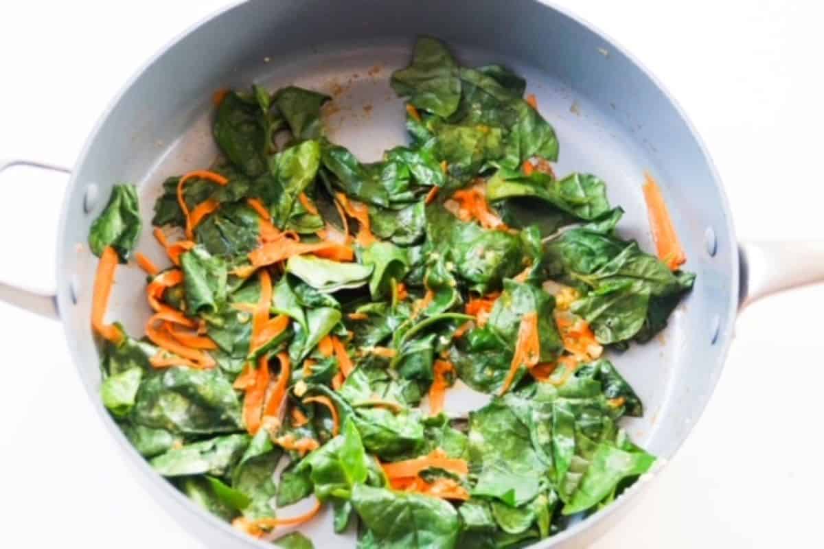 Sautéed spinach and carrots in a skillet. 