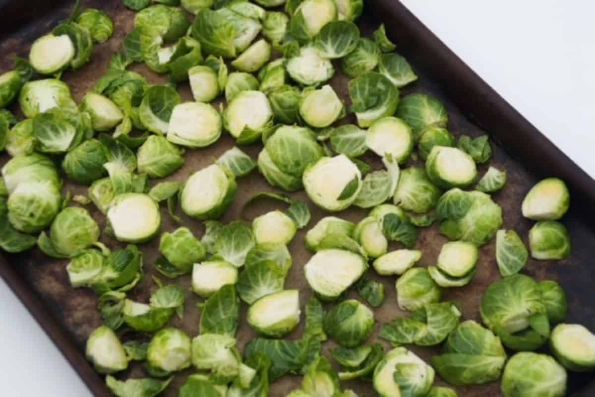 Brussel sprouts halves and leaves spread out on a rimmed baking sheet
