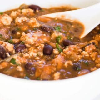 turkey chili in a white bowl with a white spoon