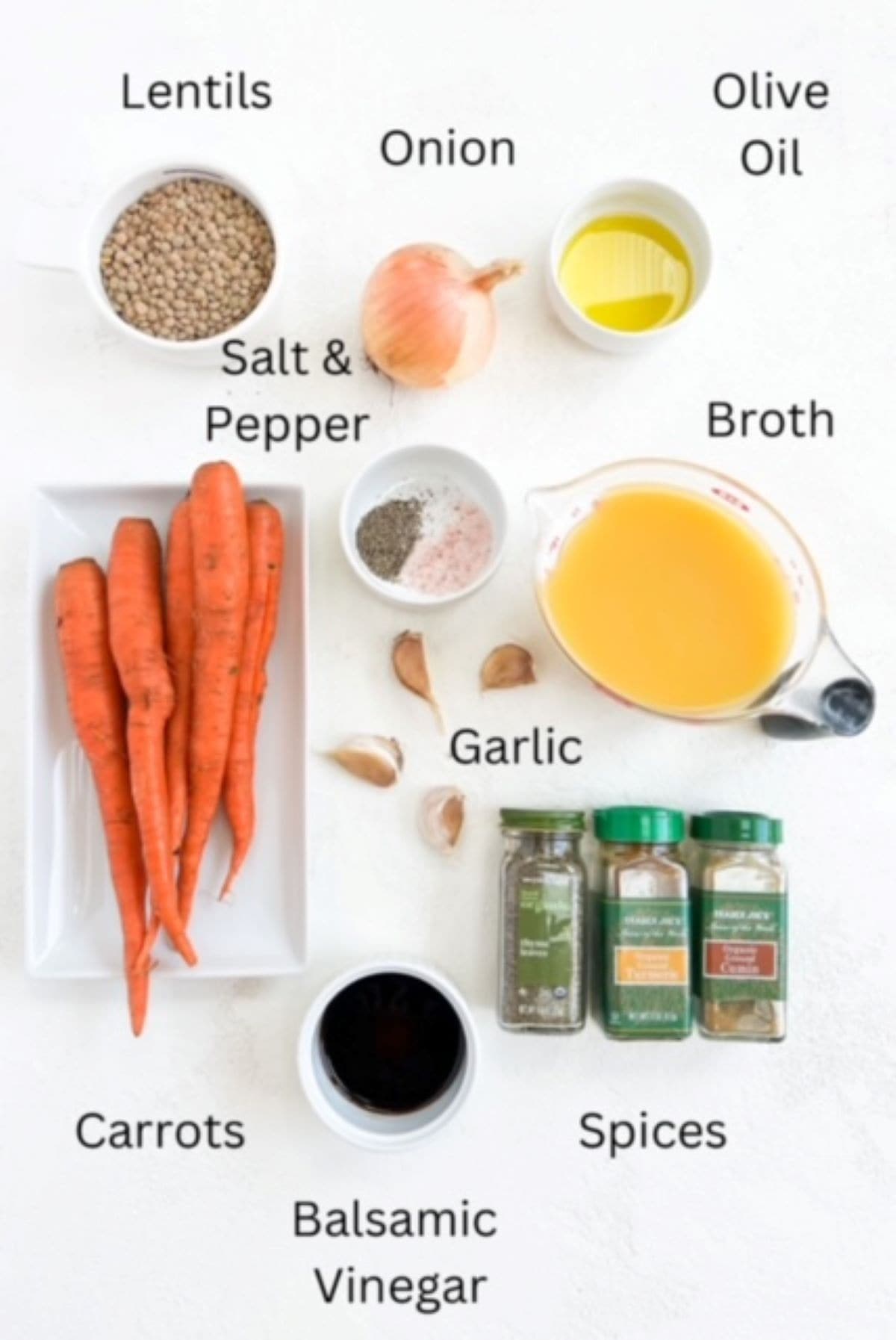 Ingredients to make Carrot and Lentil Soup on a white surface and labeled.