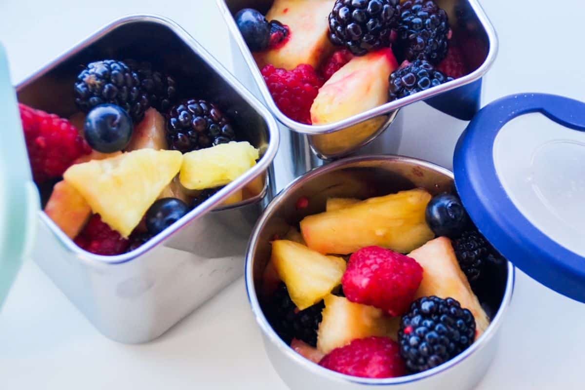 Fresh fruit salad in three separate stainless steel lunch containers with the lids off.