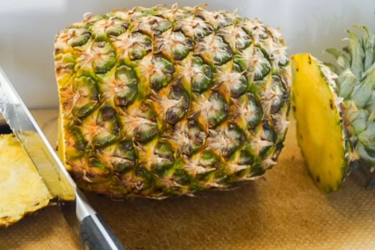 Whole pineapple laying on its side with the ends cut off.