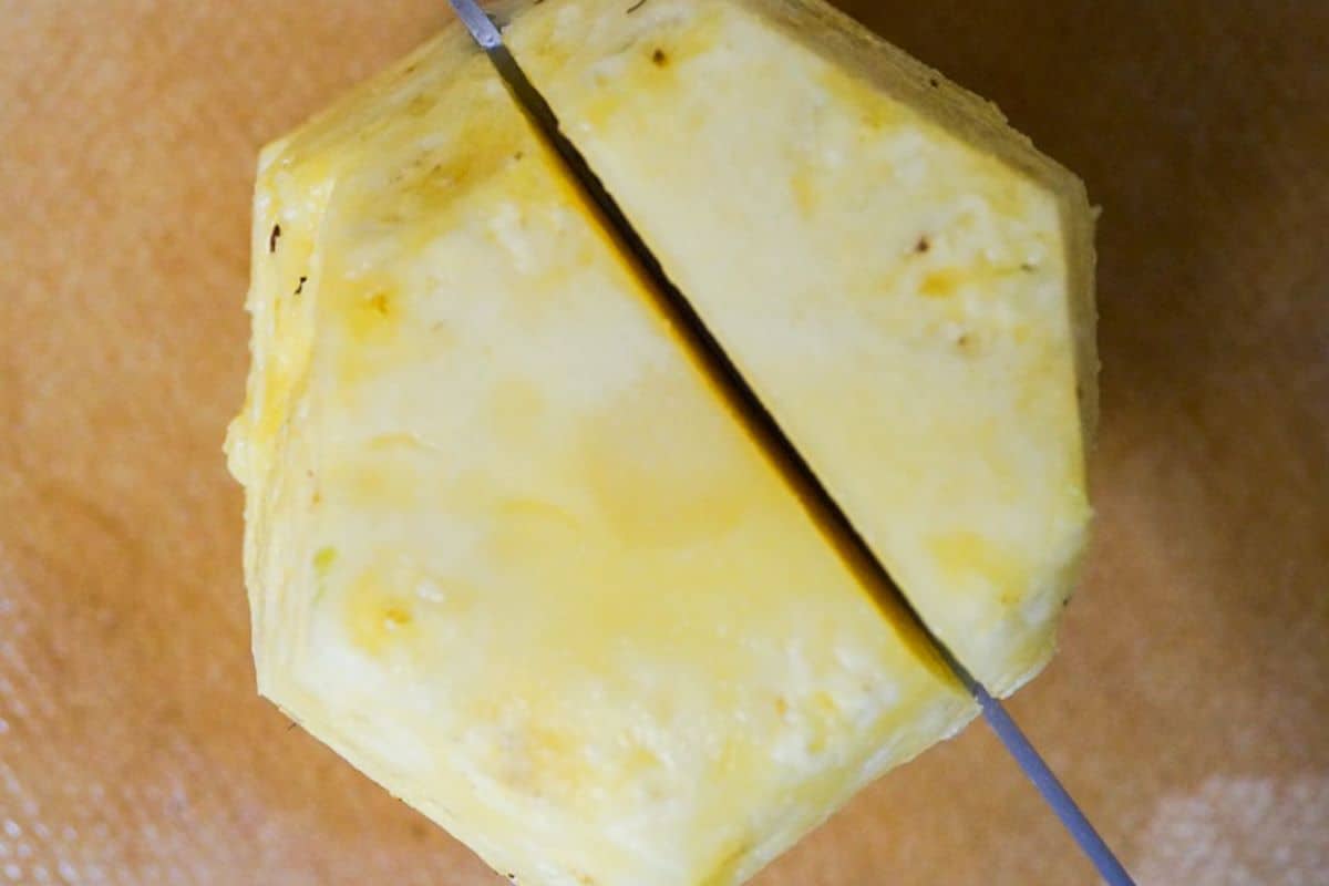 Tip view of a peeled pineapple, sliced along the core with a knife.