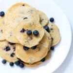 A plate of whole wheat blueberry pancakes topped with fresh blueberries.