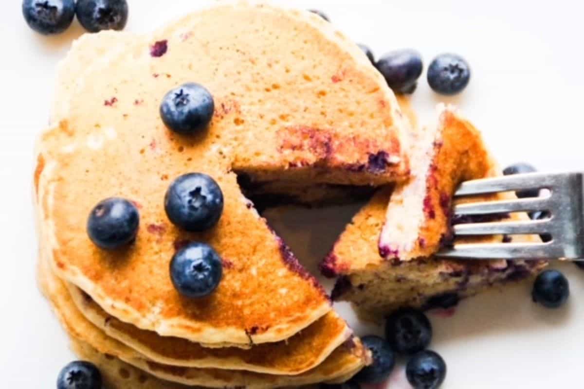 Stack of blueberry pancakes with piece cut out with a fork.