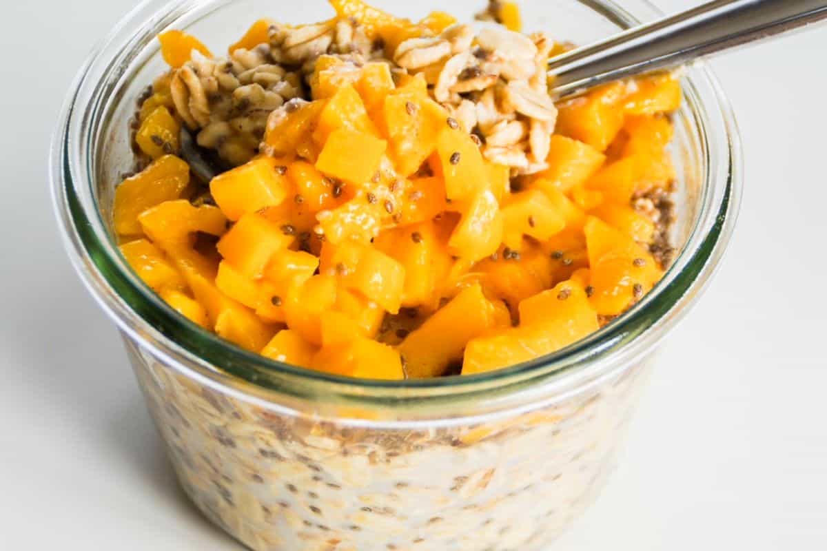 mango overnight oats in a jar with a spoon