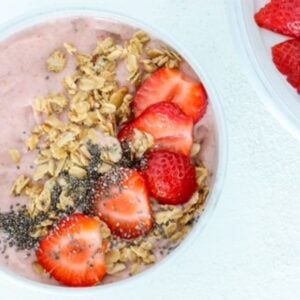 One strawberry smoothie bowl topped with granola, chia seeds, and sliced strawberries.