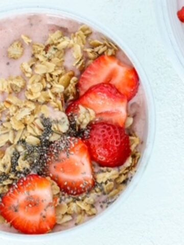 One strawberry smoothie bowl topped with granola, chia seeds, and sliced strawberries.