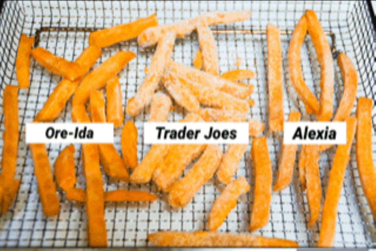 Three brands of frozen sweet potato fries, labeled, in a single layer on an air fryer basket.