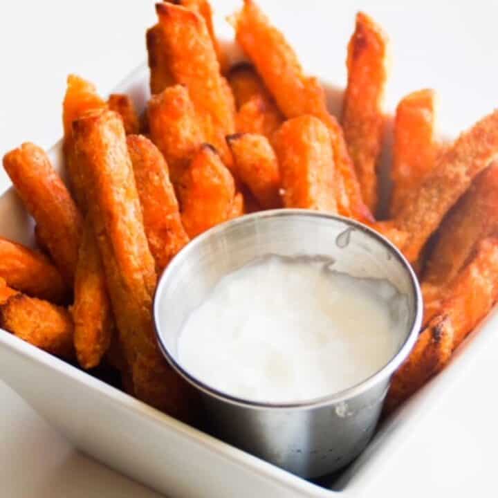 sweet potato fries in a white square bowl with yogurt for dipping