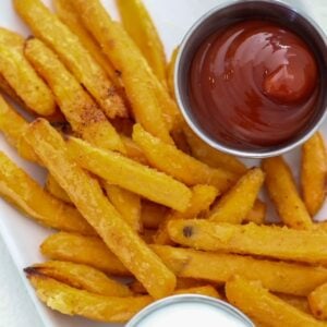 Sweet potato fries plated with ketchup and yogurt dip.