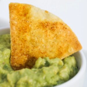 single air fried tortilla chip in guacamole