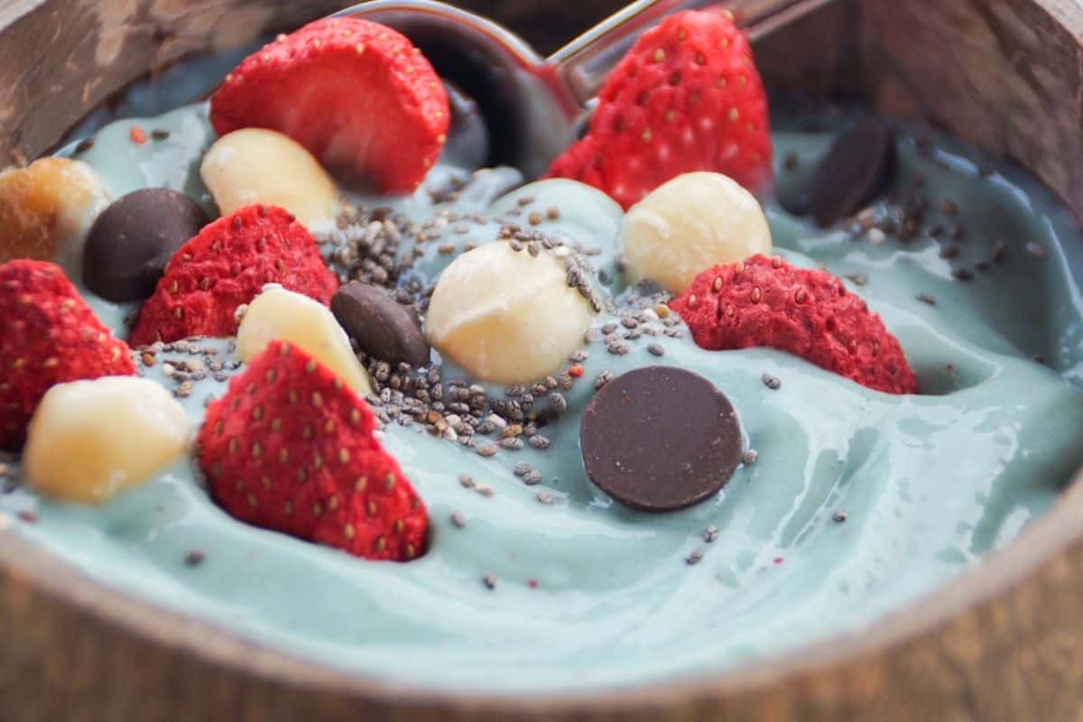 blue smoothie bowl with toppings in a coconut shell bowl