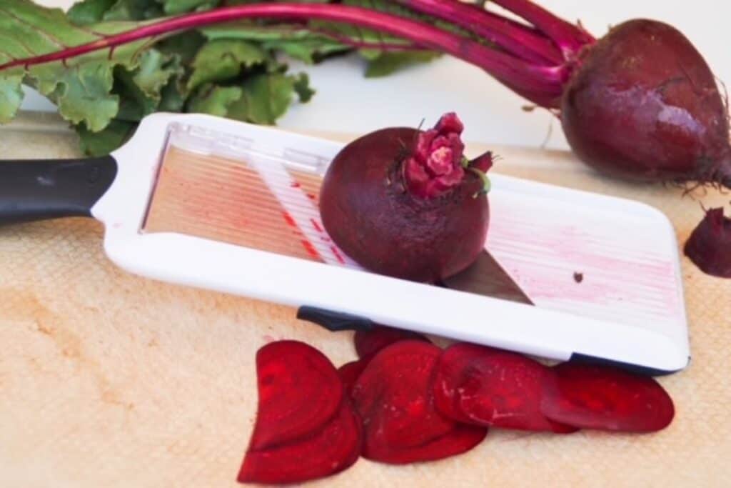 beet being sliced with a mandolin