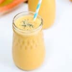One Carrot Banana Smoothie in a glass jar with a blue and white striped straw.