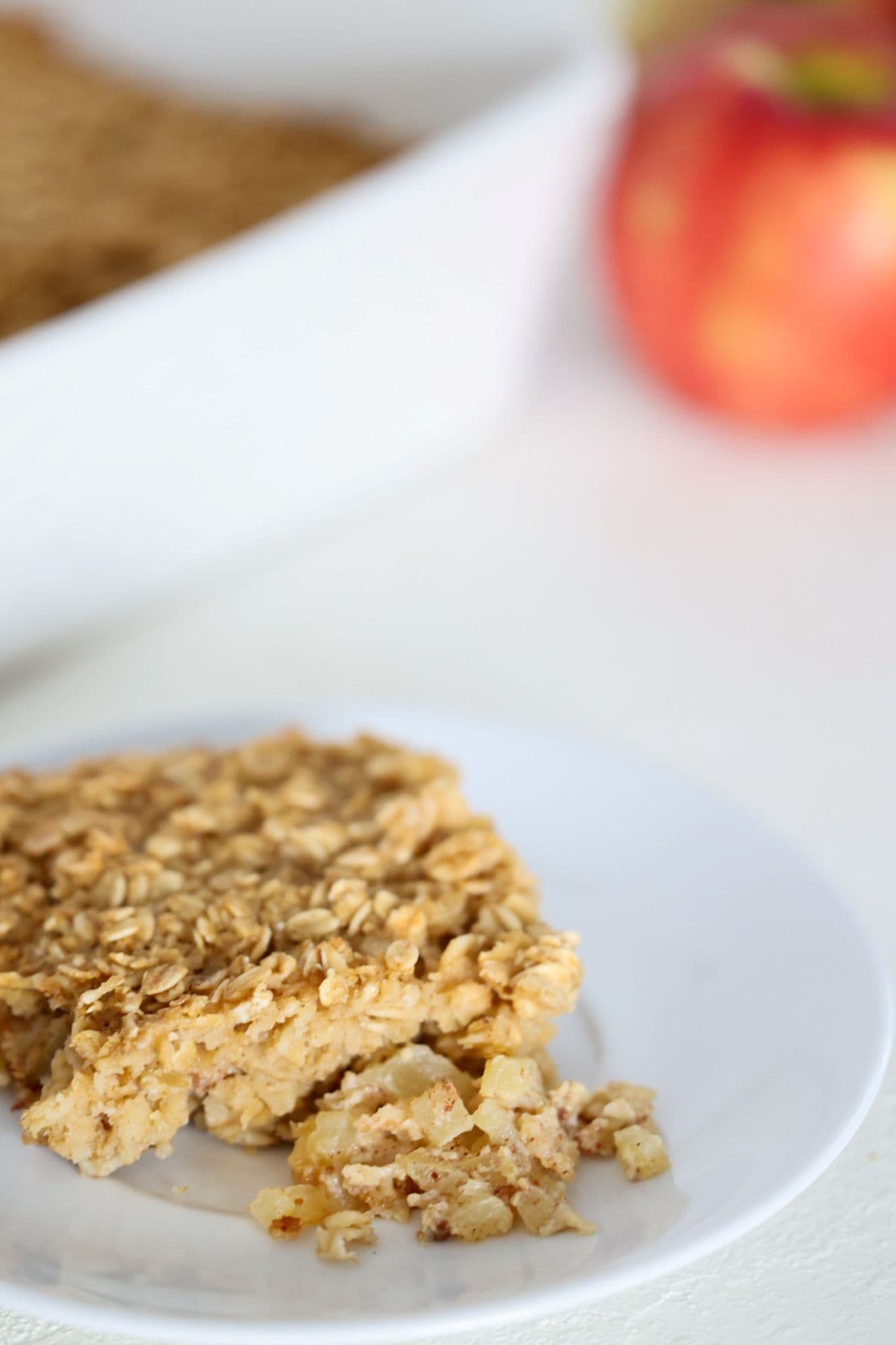 One piece of baked oatmeal with apples and cinnamon on a white plate.