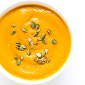 Top view of a bowl of Carrot Butternut Squash Soup topped with pumpkin seeds.