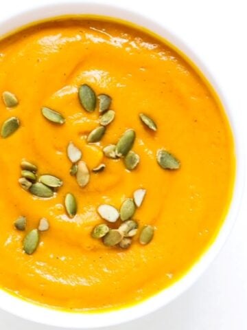 Top view of a bowl of Carrot Butternut Squash Soup topped with pumpkin seeds.