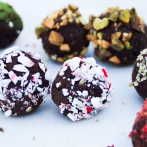 Truffles with various toppings on a white plate.