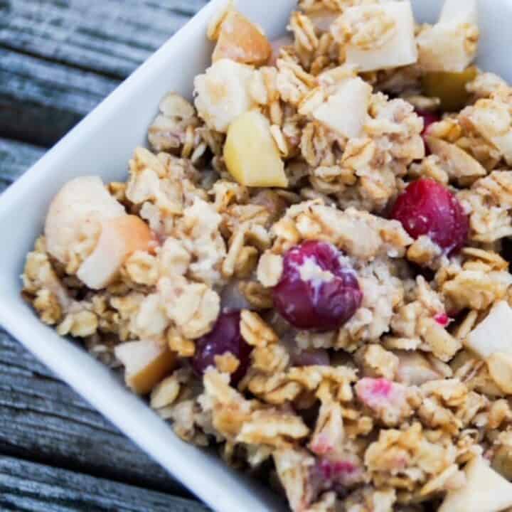 Apple baked oatmeal with cranberries in a square white bowl.