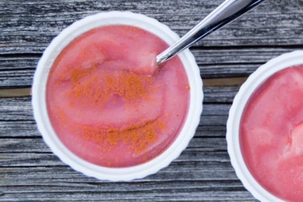 Pink applesauce in a small white bowl.
