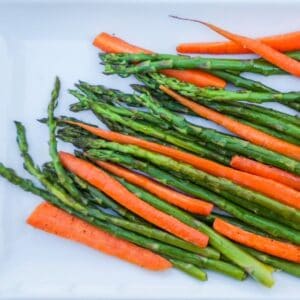 Roasted carrots and asparagus served on a white plate.