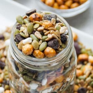 Up close image of nut free trail mix in a glass mason jar (top view). Trail mix also around the base of the glass jar.