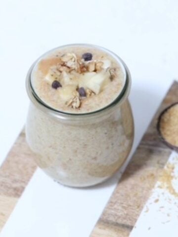 Flaxseed Pudding in a glass jar and topped with fresh banana, granola, and a few mini chocolate chips.