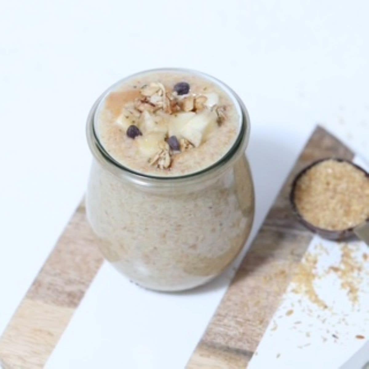 Flaxseed Pudding in a glass jar and topped with fresh banana, granola, and a few mini chocolate chips.