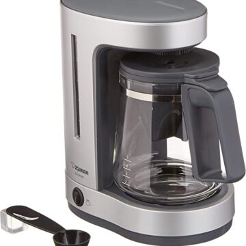 One silver 5-cup coffeemaker with a coffee scoop to the left of the coffee maker.