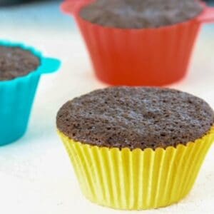Three dairy-free chocolate cupcakes in colorful cupcake liners.