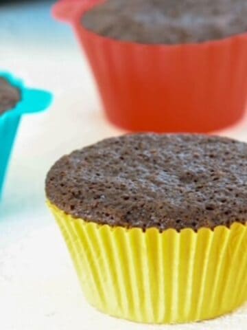 Three dairy-free chocolate cupcakes in colorful cupcake liners.