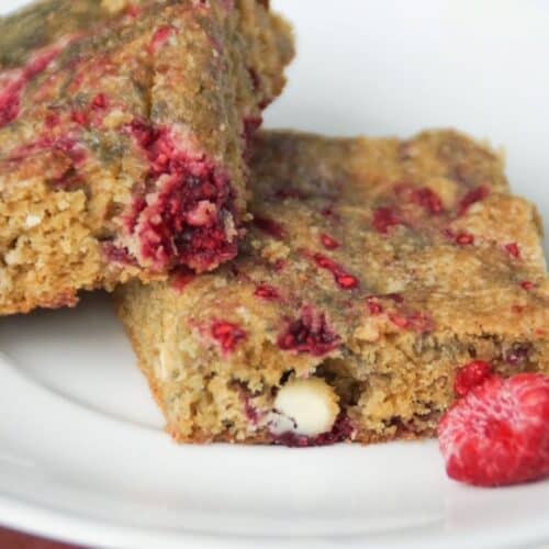 Two Raspberry and White Chocolate Blondies on a small white plate.