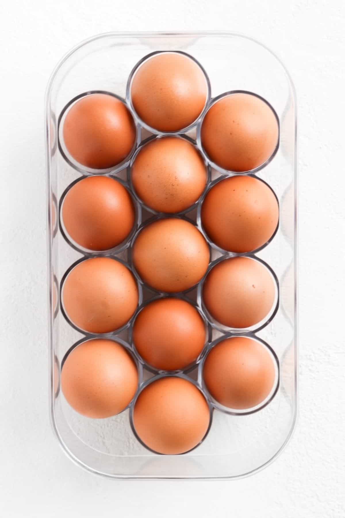 Fourteen brown eggs in a plastic egg holder.