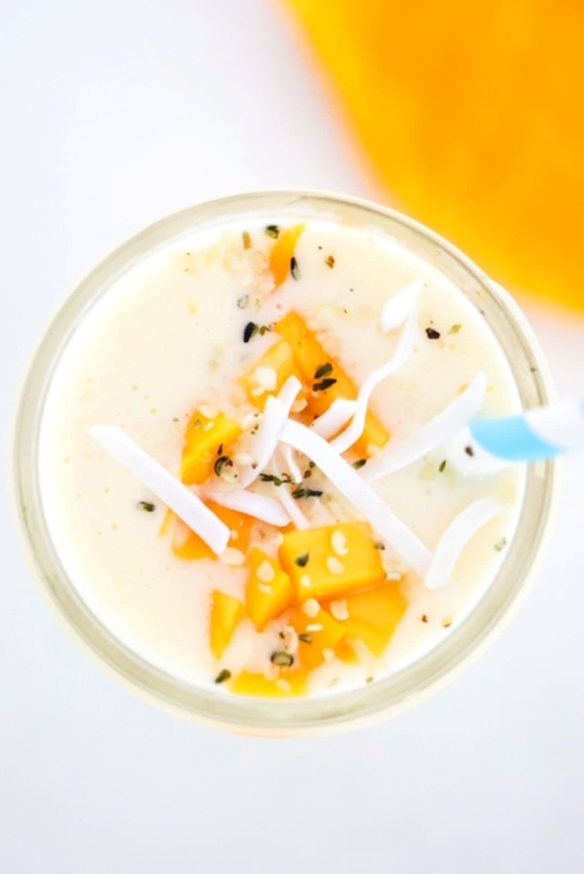 Mango Pineapple Smoothie topped with mango pieces and coconut flakes.