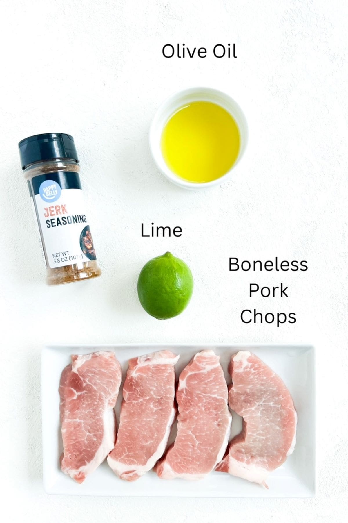 Four boneless pork chops, olive oil, one lime, labeled and a container of jerk seasoning on a white background.