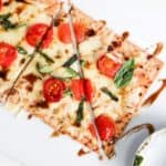 One margherita flatbread sliced. A pizza roller is to the right of the flatbread.