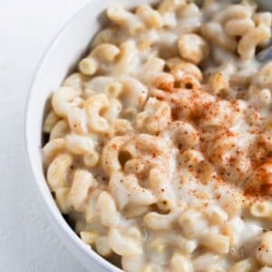 White cheddar mac and cheese topped with Old Bay seasoning and served in a white bowl.