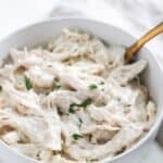 Chicken in white sauce served in a white bowl with a golden spoon.