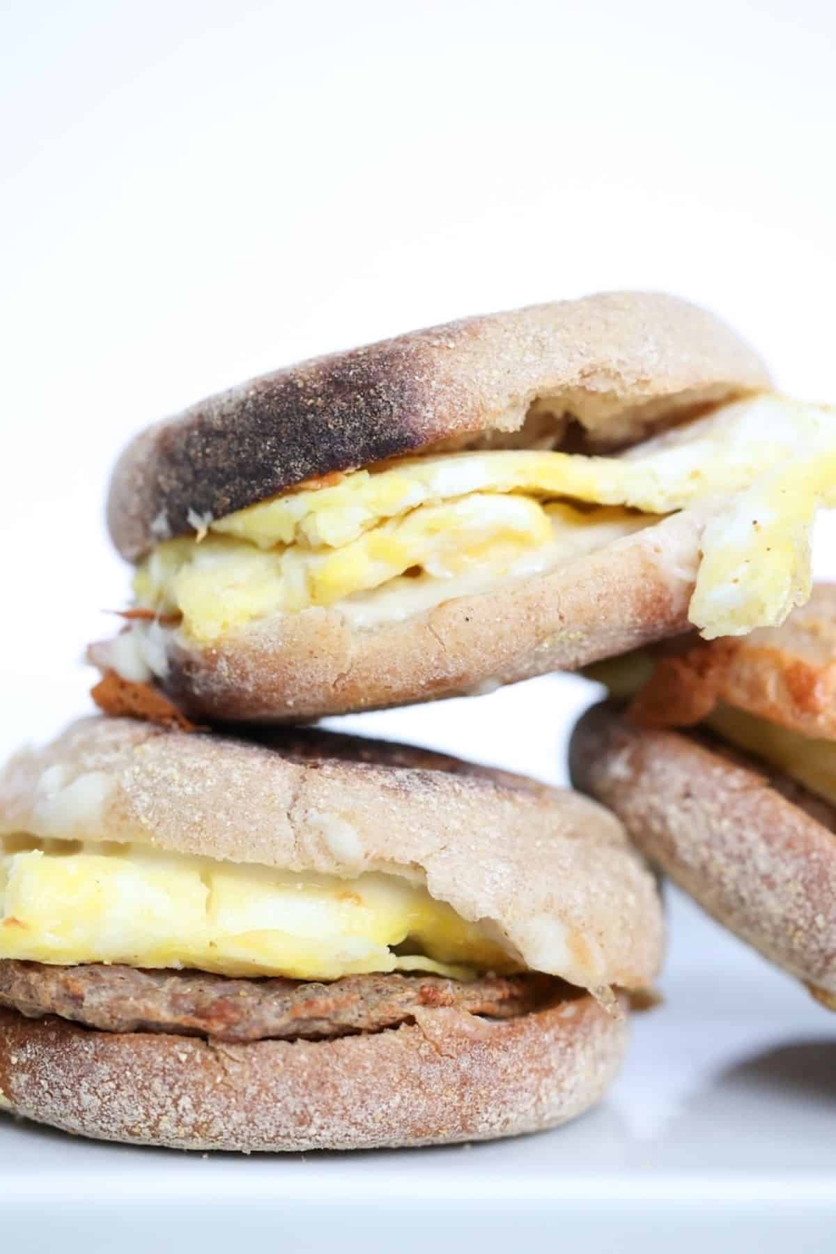 Three sausage, egg, and cheese sandwiches stacked.