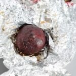 One roasted beet on top of a piece of foil.