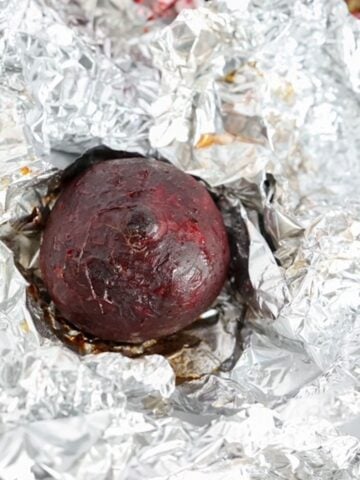 One roasted beet on top of a piece of foil.