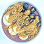 One acai protein bowl topped with toppings served in a white bowl.
