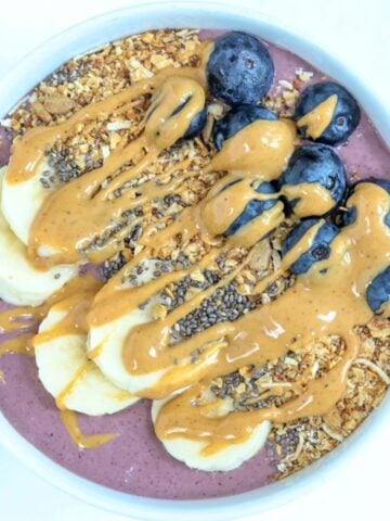 One acai protein bowl topped with toppings served in a white bowl.